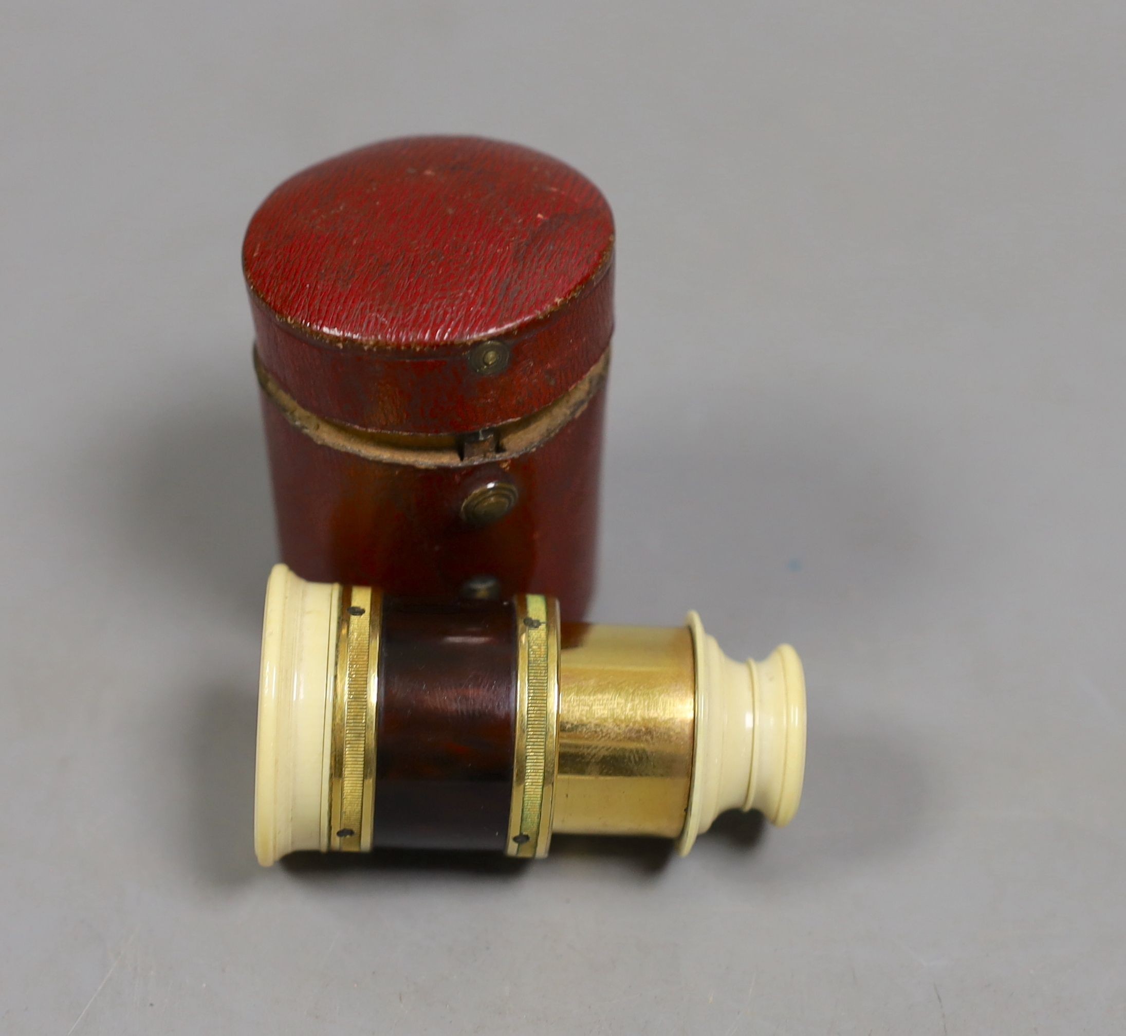 A 19th century ivory and tortoiseshell monocular in red leather case., Monocular 4.5 cms high, case 5.5 cms high.